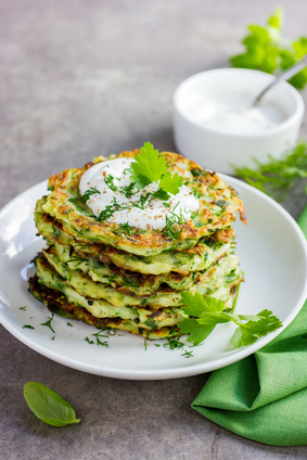 zucchini fritters, vegetarian zucchini pancakes, served with fresh herbs and garlic yogurt sauce, selective focus
