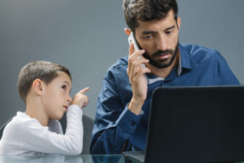 Father on laptop ignoring son while the child tries to catch his attention