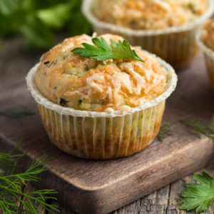 savory muffins with zucchini and cheese on wooden background, selective focus, square image