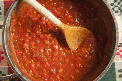 A pot of tomato sauce with a wooden spoon