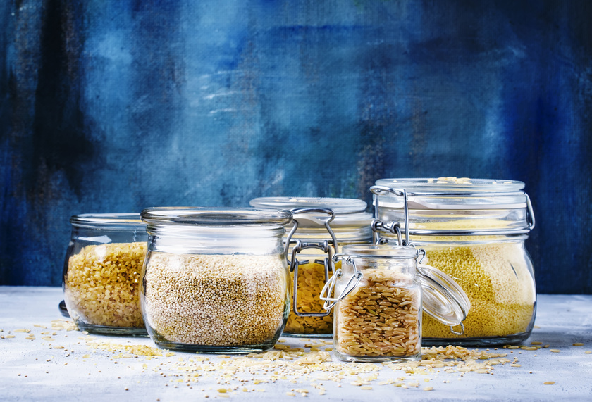 Assorted cereals in glass jars: kinoa, bulgur, couscous, orzo, brown rice, selective focus
