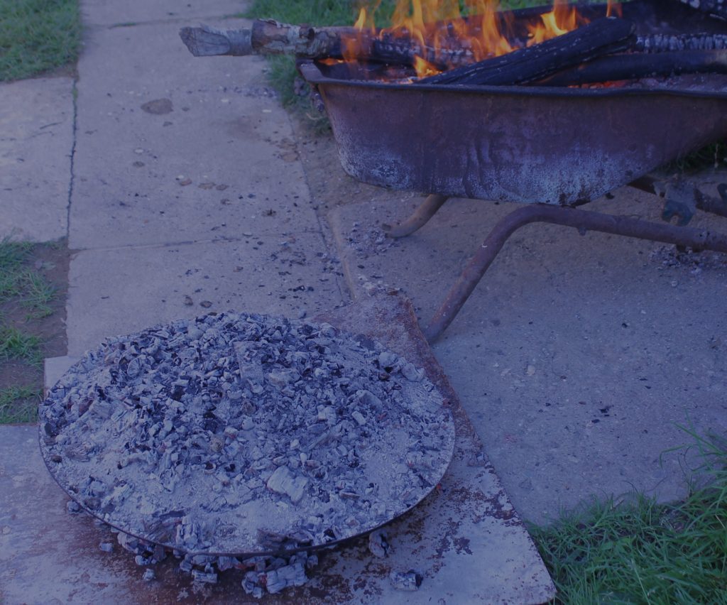 Hot coals are piled on the lid of the pan to cook the top of the pancake