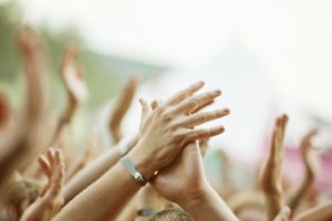 The hands of a concert crowd at a live music show, focus on the hand in the foreground