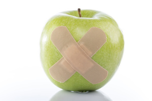Green apple with a band-aid on white background