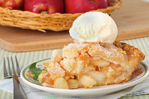 Closeup of a slice of apple pie with a scoop of ice cream on a plate