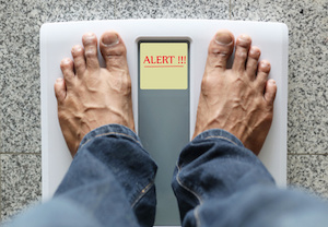 Man standing on weight scale with text: Alert