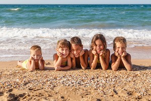 Five smiling kids enjoying on the beach