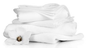 Stack of clean bedding sheets and towels isolated on white