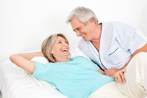 Zwei Senioren liegen lachend im Bett im Schlafzimmer