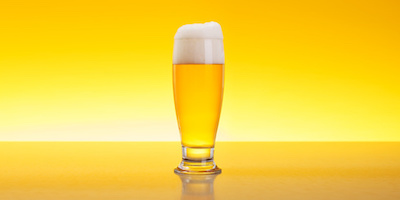 Alcoholic beverage in glass over yellow background