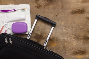 Suitcase traveler, toiletries on a wooden background.