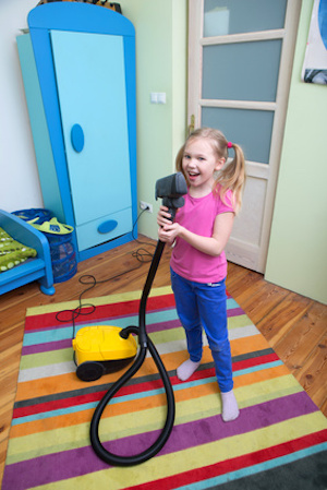 Girl sings while she tidies up the room with vacuum cleaner, girl cleaning floor with hoover