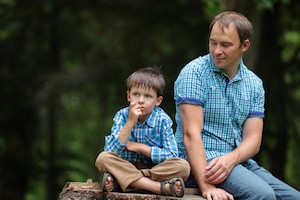 Happy father and son talking and having rest outdoors in city on beautiful summer day