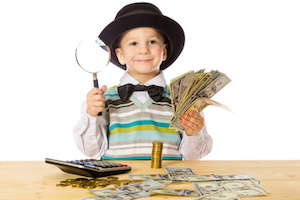 Smiling little boy in black hat counting money on the table, isolated on white