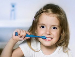 Child girl cleaning teeth with toothbrush in the bathroom.