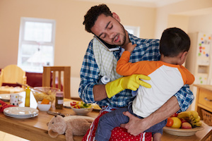 Busy Father Looking After Son Whilst Doing Household Chores
