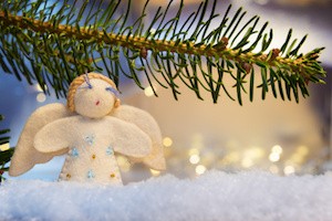 Image of a branch with felt angel on artificial snow and bokeh lights in background