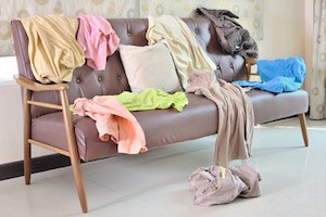 Messy clothes scattered on a sofa in living room
