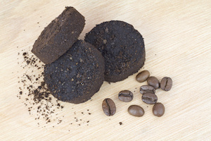 Used coffee grounds after espresso machine and coffee beans on wooden background.