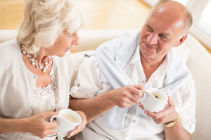 Happy senior couple drinking coffee at home