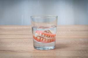 False teeth swim in transparent water glass - dental concept