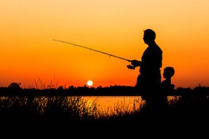 father and son fishing in the river sunset backgrond
