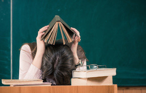 tired teacher with open book above head
