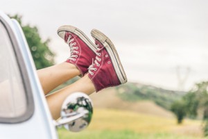 Woman relaxing in her car while driving in the countryside - Young  cool girl with shoes out of the automobile window to enjoy the view