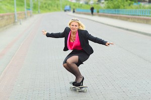 Senior business woman having fun on a skateboard outdoors