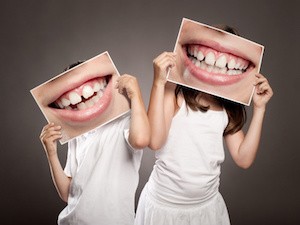 two children holding a picture of a mouth smiling