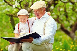 grandfather with grandson reading book in spring garden