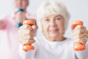 Elderly woman exercising with dumbbells.