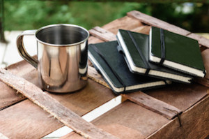 cup of coffee with notepads on brown wood table background
