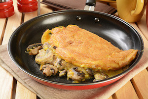 An omelet with sauteed mushrooms and cheeses in a frying pan