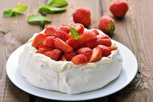 Pavlova cake with strawberry on wooden table