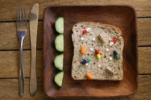 Various drugs and pills on a slice of granary bread on a wooden plate at a table setting