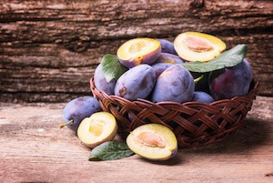Fresh plums on wooden background .