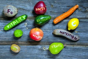 scattered fruits and vegetables with cut words - healthy lifestyle concept