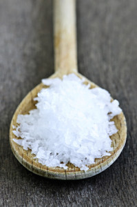 Sea salt on wooden spoon over wooden table background