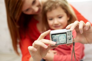 people, family and technology concept - close up of happy mother and little daughter with camera taking selfie