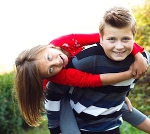 Siblings having fun - boy carrying his sister on his back.