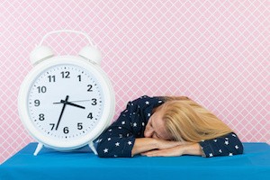 Woman of mature age laying next to big alarm clock