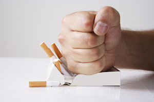 Hand crushing cigarettes over white background