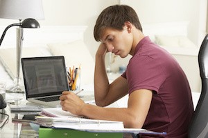 Teenage Boy Studying At Desk In Bedroom