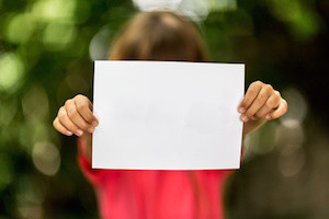 Blurred girl holding a blank piece of paper with copy space in front of her.