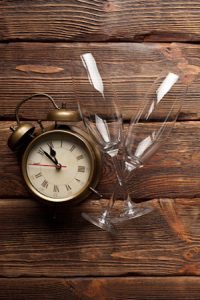 Alarm clock and two empty glasses on wooden background